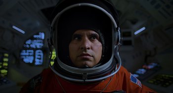 Movie still from “A Million Miles Away” (2023), directed by Alejandra Márquez Abella – A man in a space suit is looking at the camera; Close Up shot, Low angle
