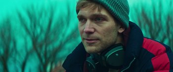 Movie still from “A Night at the Kindergarten” (2022), directed by Rafal Skalski – A person wearing headphones; Close Up shot, Low angle