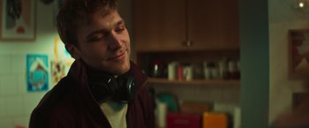 Movie still from “A Night at the Kindergarten” (2022), directed by Rafal Skalski – A young man with headphones is listening to music in a kitchen; Close Up shot, Low angle