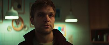 Movie still from “A Night at the Kindergarten” (2022), directed by Rafal Skalski – A person wearing a brown jacket; Close Up shot, Low angle