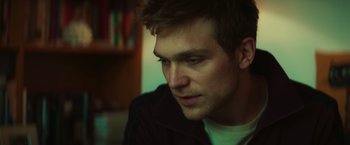 Movie still from “A Night at the Kindergarten” (2022), directed by Rafal Skalski – A man's face in a dark room; Close Up shot, Low angle