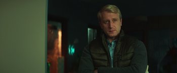 Movie still from “A Night at the Kindergarten” (2022), directed by Rafal Skalski – A person wearing a jacket; Close Up shot, Over the shoulder angle