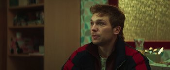 Movie still from “A Night at the Kindergarten” (2022), directed by Rafal Skalski – A young man is sitting in front of a wall; Close Up shot, Low angle