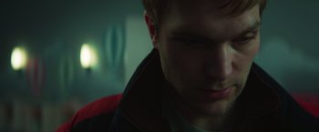 Movie still from “A Night at the Kindergarten” (2022), directed by Rafal Skalski – A man's face in a dark room; Close Up shot, Low angle