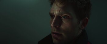 Movie still from “A Night at the Kindergarten” (2022), directed by Rafal Skalski – A person's face with a dark background; Close Up shot, Low angle