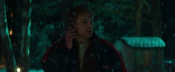 Movie still from “A Night at the Kindergarten” (2022), directed by Rafal Skalski – A young man talking on a cell phone in the snow; Close Up shot, Low angle