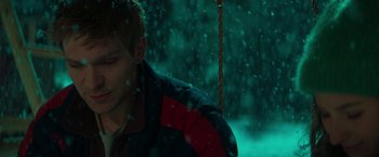 Movie still from “A Night at the Kindergarten” (2022), directed by Rafal Skalski – A man sitting on top of a swing in the snow; Close Up shot, High angle