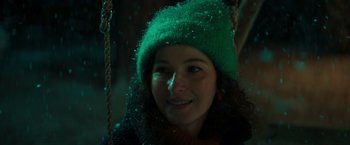 Movie still from “A Night at the Kindergarten” (2022), directed by Rafal Skalski – A woman wearing a green hat and smiling for the camera; Close Up shot, Low angle