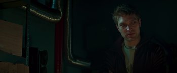 Movie still from “A Night at the Kindergarten” (2022), directed by Rafal Skalski – A man in a black jacket is in a dark room; Close Up shot, Low angle