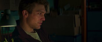 Movie still from “A Night at the Kindergarten” (2022), directed by Rafal Skalski – A person sitting in a room; Close Up shot, Low angle