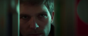 Movie still from “A Night at the Kindergarten” (2022), directed by Rafal Skalski – A man's face in the dark; Close Up shot, Low angle