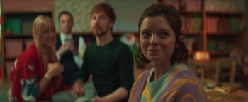 Movie still from “A Night at the Kindergarten” (2022), directed by Rafal Skalski – A woman sitting in front of two other people; Close Up shot, Over the shoulder angle