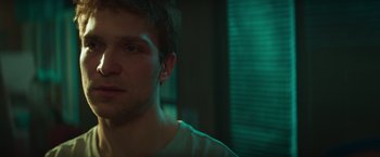 Movie still from “A Night at the Kindergarten” (2022), directed by Rafal Skalski – A person wearing a white t - shirt; Close Up shot, Over the shoulder angle