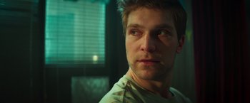 Movie still from “A Night at the Kindergarten” (2022), directed by Rafal Skalski – A man's face in the dark; Close Up shot, Low angle