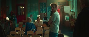 Movie still from “A Night at the Kindergarten” (2022), directed by Rafal Skalski – A group of people sitting in chairs in a room; Medium shot, Over the shoulder angle