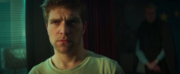 Movie still from “A Night at the Kindergarten” (2022), directed by Rafal Skalski – A person wearing a white t - shirt; Close Up shot, Low angle