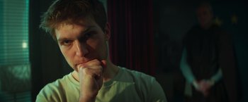 Movie still from “A Night at the Kindergarten” (2022), directed by Rafal Skalski – A man with his chin resting on his hand; Close Up shot, Low angle