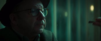 Movie still from “A Night at the Kindergarten” (2022), directed by Rafal Skalski – An older man wearing glasses and a hat; Close Up shot, Over the shoulder angle
