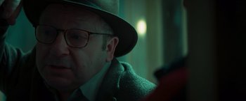 Movie still from “A Night at the Kindergarten” (2022), directed by Rafal Skalski – An older man wearing a hat looking at his cell phone; Close Up shot, Over the shoulder angle