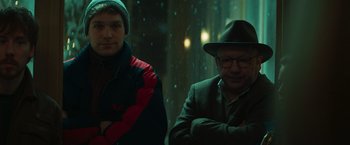 Movie still from “A Night at the Kindergarten” (2022), directed by Rafal Skalski – A man and a man in a hat and jacket; Medium shot, Low angle
