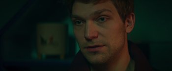 Movie still from “A Night at the Kindergarten” (2022), directed by Rafal Skalski – A man's face in a dark room; Extreme Close Up shot, Over the shoulder angle