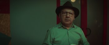 Movie still from “A Night at the Kindergarten” (2022), directed by Rafal Skalski – An older man wearing glasses and a hat; Close Up shot, Over the shoulder angle