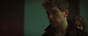 Movie still from “A Night at the Kindergarten” (2022), directed by Rafal Skalski – A person with curly hair; Close Up shot, Low angle