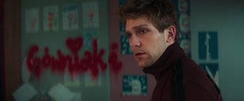 Movie still from “A Night at the Kindergarten” (2022), directed by Rafal Skalski – A man with a beard and a jacket looking at the camera; Close Up shot, Over the shoulder angle