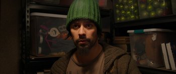 A man wearing a green hat and a brown jacket