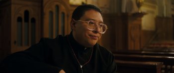A man wearing glasses sitting in front of an organ