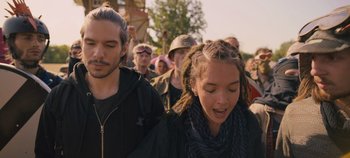 Movie still from “A Place to Fight For” (2023), directed by Romain Cogitore – A group of people walking down a street; Close Up shot, Over the shoulder angle