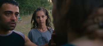 Movie still from “A Place to Fight For” (2023), directed by Romain Cogitore – A woman with dreads looking into a mirror; Close Up shot, Over the shoulder angle