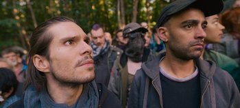 Movie still from “A Place to Fight For” (2023), directed by Romain Cogitore – A group of men standing next to each other in a forest; Close Up shot, Over the shoulder angle