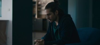 Movie still from “A Place to Fight For” (2023), directed by Romain Cogitore – A man sitting down looking down at his cell phone; Close Up shot, Over the shoulder angle