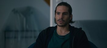 Movie still from “A Place to Fight For” (2023), directed by Romain Cogitore – A person sitting in a chair; Close Up shot, Over the shoulder angle