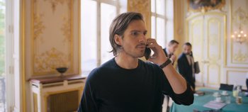 Movie still from “A Place to Fight For” (2023), directed by Romain Cogitore – A man talking on a cell phone while standing in front of a window; Close Up shot, Over the shoulder angle