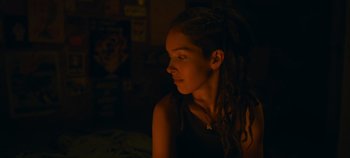 Movie still from “A Place to Fight For” (2023), directed by Romain Cogitore – A woman with dreads sitting in a dark room; Close Up shot, Over the shoulder angle