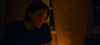 Movie still from “A Place to Fight For” (2023), directed by Romain Cogitore – A man with long dark hair looking down at the floor; Close Up shot, Low angle