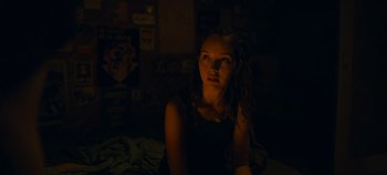 Movie still from “A Place to Fight For” (2023), directed by Romain Cogitore – A woman sitting on a bed in a dark room; Close Up shot, Over the shoulder angle