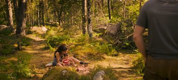 Movie still from “A Place to Fight For” (2023), directed by Romain Cogitore – A woman and a child sitting on the ground in the woods; Wide shot, High angle