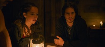 Movie still from “A Place to Fight For” (2023), directed by Romain Cogitore – A man and a woman sitting next to a lit candle; Medium shot, Over the shoulder angle