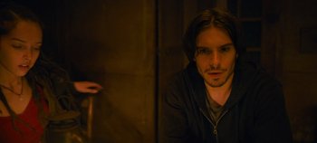 Movie still from “A Place to Fight For” (2023), directed by Romain Cogitore – A man sitting in front of a wooden wall; Close Up shot, Over the shoulder angle
