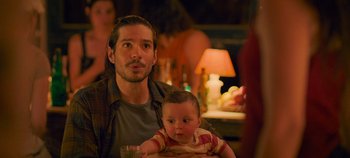 Movie still from “A Place to Fight For” (2023), directed by Romain Cogitore – A man holding a baby in his arms; Close Up shot, Over the shoulder angle