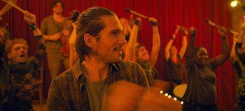 Movie still from “A Place to Fight For” (2023), directed by Romain Cogitore – A group of people in a room with musical instruments; Close Up shot, Over the shoulder angle