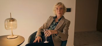 Movie still from “A Place to Fight For” (2023), directed by Romain Cogitore – A woman sitting in a chair holding a wine glass; Medium shot, Low angle