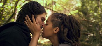 Movie still from “A Place to Fight For” (2023), directed by Romain Cogitore – Two people kissing each other in the forest; Close Up shot, Low angle