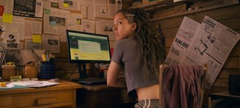 Movie still from “A Place to Fight For” (2023), directed by Romain Cogitore – A girl with dreadlocks sitting in front of a computer; Medium shot, Over the shoulder angle