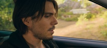 Movie still from “A Place to Fight For” (2023), directed by Romain Cogitore – A person sitting in a car looking out the window; Close Up shot, Over the shoulder angle