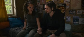 Movie still from “A Place to Fight For” (2023), directed by Romain Cogitore – A man and a woman sitting on a couch holding hands; Medium shot, High angle