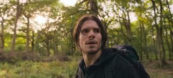 Movie still from “A Place to Fight For” (2023), directed by Romain Cogitore – A person with a backpack in the woods; Close Up shot, Low angle